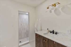 Bathroom with tiled shower, tile patterned flooring, and vanity