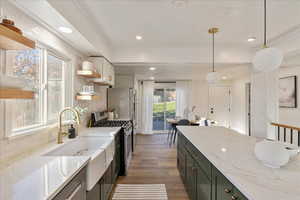 Kitchen featuring dark wood-type flooring, decorative backsplash, hanging light fixtures, stainless steel gas stove, and light stone countertops