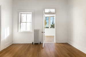 Doorway to bonus room featuring dark wood-type flooring, radiator, and plenty of natural light