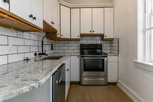 Kitchen with white cabinets, stainless steel appliances, sink, and tasteful backsplash