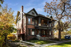 View of front of home with a balcony, a front yard, and a porch