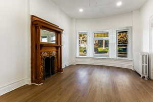 Living room with dark hardwood / wood-style floors and radiator heating unit