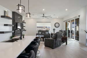 Living room with light wood-type flooring, ceiling fan, and sink