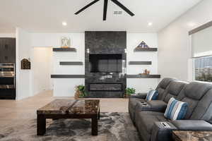 Living room with ceiling fan, light wood-type flooring, and a premium fireplace