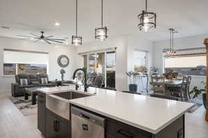 Kitchen featuring light wood-type flooring, ceiling fan, sink, a center island with sink, and dishwasher