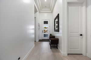 Hallway featuring light wood-type flooring and a raised ceiling