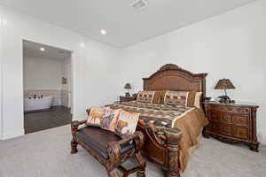 Carpeted bedroom featuring ensuite bathroom and tile walls