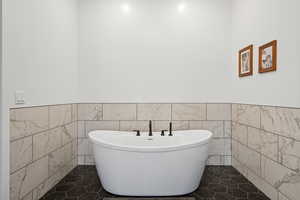 Bathroom with tile walls, tile patterned flooring, and a bathing tub