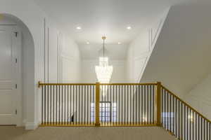 Hall featuring carpet, an inviting chandelier, and lofted ceiling