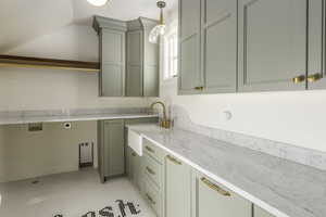 Kitchen with decorative light fixtures, light stone countertops, and sink