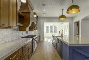 Kitchen with a kitchen island with sink, light hardwood / wood-style flooring, decorative backsplash, decorative light fixtures, and a chandelier