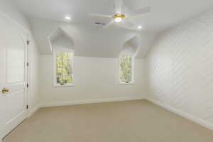 Additional living space with light carpet, a wealth of natural light, lofted ceiling, and ceiling fan