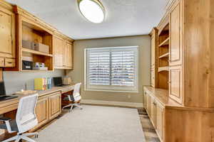 Office space featuring built in desk, a textured ceiling, and light wood-type flooring