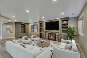 Living room with built in features, a fireplace, and light hardwood / wood-style flooring