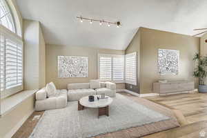 Living room featuring light wood-type flooring, track lighting, and vaulted ceiling