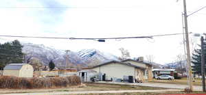 View of side of home with a mountain view and a storage shed