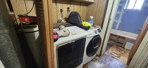 Laundry area with washer and clothes dryer and wood walls