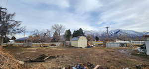 View of yard featuring a mountain view, a fenced in pool, and a storage unit