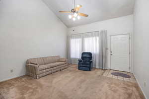 Living room featuring high vaulted ceiling, ceiling fan, and carpet floors