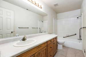 Full bathroom featuring tile patterned flooring, tiled shower / bath, a textured ceiling, vanity, and toilet