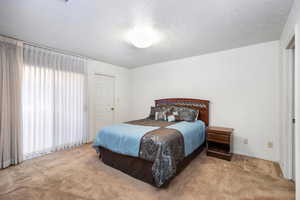 Bedroom with a textured ceiling and light carpet