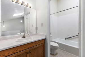 Full bathroom featuring tile patterned floors, toilet, vanity, a skylight, and shower / bathtub combination