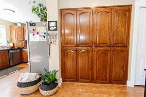 Kitchen with light wood-type flooring and appliances with stainless steel finishes