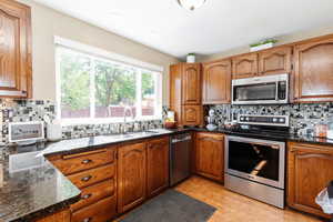 Kitchen with stainless steel appliances, sink, light wood-type flooring, and decorative backsplash