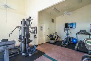 Exercise area featuring high vaulted ceiling, dark colored carpet, and ceiling fan