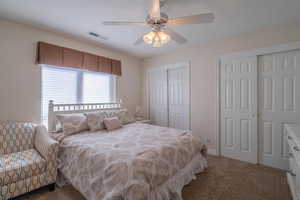 Carpeted 3rd bedroom with ceiling fan and multiple closets