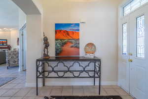 Entrance foyer with light tile patterned floors and crown molding