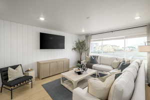 Living room with light hardwood / wood-style flooring and wood walls