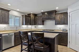 Kitchen featuring light hardwood / wood-style flooring, sink, a kitchen breakfast bar, a kitchen island, and appliances with stainless steel finishes