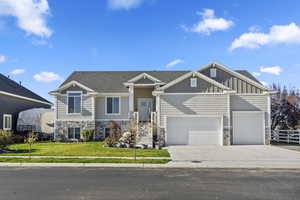 Craftsman inspired home with a garage and a front lawn