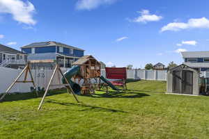 View of play area with a lawn and a storage shed