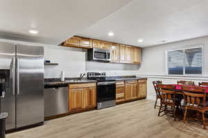 Kitchen with light hardwood / wood-style flooring, sink, and stainless steel appliances