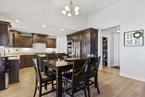 Dining area featuring high vaulted ceiling, light wood-type flooring, sink, and a notable chandelier