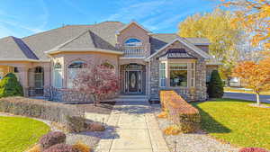 View of front of property with a balcony and a front lawn