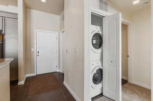 Laundry room featuring stacked washer / dryer and dark tile patterned floors