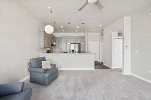 Kitchen with stainless steel appliances, gray cabinets, light colored carpet, and decorative light fixtures