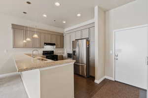 Kitchen with appliances with stainless steel finishes, dark tile patterned flooring, pendant lighting, sink, and kitchen peninsula