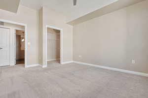 Unfurnished bedroom with light carpet, a closet, and a spacious closet