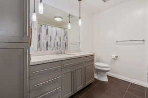 Bathroom with toilet, vanity, a shower with shower curtain, and tile patterned floors