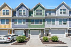 View of property featuring a garage and landscaped yard