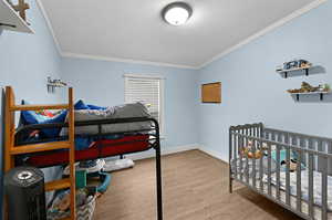 Bedroom featuring ornamental molding, light hardwood / wood-style floors, and a textured ceiling