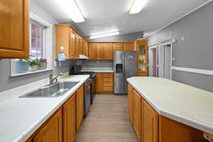 Kitchen with light hardwood / wood-style floors, stainless steel appliances, lofted ceiling, a textured ceiling, and sink