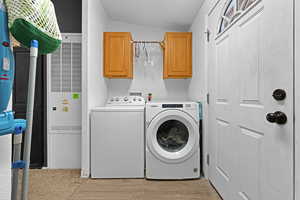 Clothes washing area featuring light hardwood / wood-style flooring, cabinets, and washing machine and clothes dryer