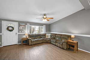 Living room with ornamental molding, wood-type flooring, and ceiling fan