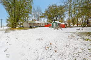 Yard covered in snow featuring a shed