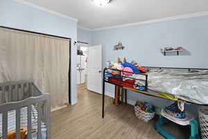 Bedroom featuring light wood-type flooring and crown molding